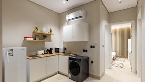 A compact kitchen with a washing machine, microwave, and a refrigerator.