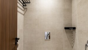 Een moderne badkamer met een toilet, een douchegedeelte en een houten deur.