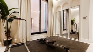 A room with a treadmill, a large mirror, and a potted plant. - Two Bedroom Luxury Flat in Al-narjis (Riyadh)