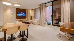 A modern living room with a TV, sofa, dining table, and chairs. - Two Bedroom Luxury Flat in Al-narjis (Riyadh)