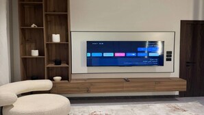 Een moderne woonkamer met een grote flatscreen-tv bevestigd aan een houten wandmeubel.