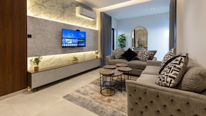 Een moderne woonkamer met een bank, salontafel en een televisie bevestigd aan een gestructureerde muur.