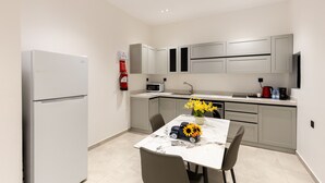 Een moderne keuken met een koelkast, magnetron, spoelbak en een eettafel met stoelen.