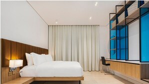 Een moderne hotelkamer met een bed, nachtkastje, lamp en een inbouwtelevisieplank.