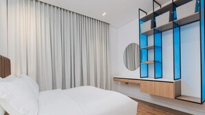 A modern bedroom with a bed, a built-in wardrobe, and a round mirror. - Stylish 1-br Apartment in Almughrizat (Riyadh)