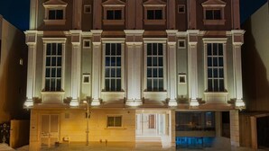 Un edificio grande de varios pisos con fachada simétrica, amplias ventanas y una entrada central.
