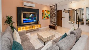 A modern living room with a flat-screen TV, a sofa set, a coffee table, and decorative plants. - Luxury & Elegant Apartment in Almughrizat (Riyadh)