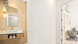 A modern bathroom with a wooden vanity, a large mirror, and a white sink. - Luxury & Elegant Apartment in Almughrizat (Riyadh)