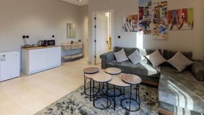 A modern living room with a grey sofa, a coffee table, and a kitchen area with a microwave and cabinets. - Cozy One BR in Almadinah With Upscale Luxury (Madinah)
