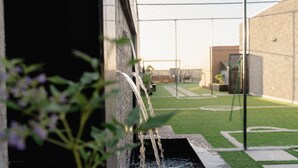 A modern building with a water feature, green artificial turf, and a clear sky. - Cozy One BR in Almadinah With Upscale Luxury (Madinah)