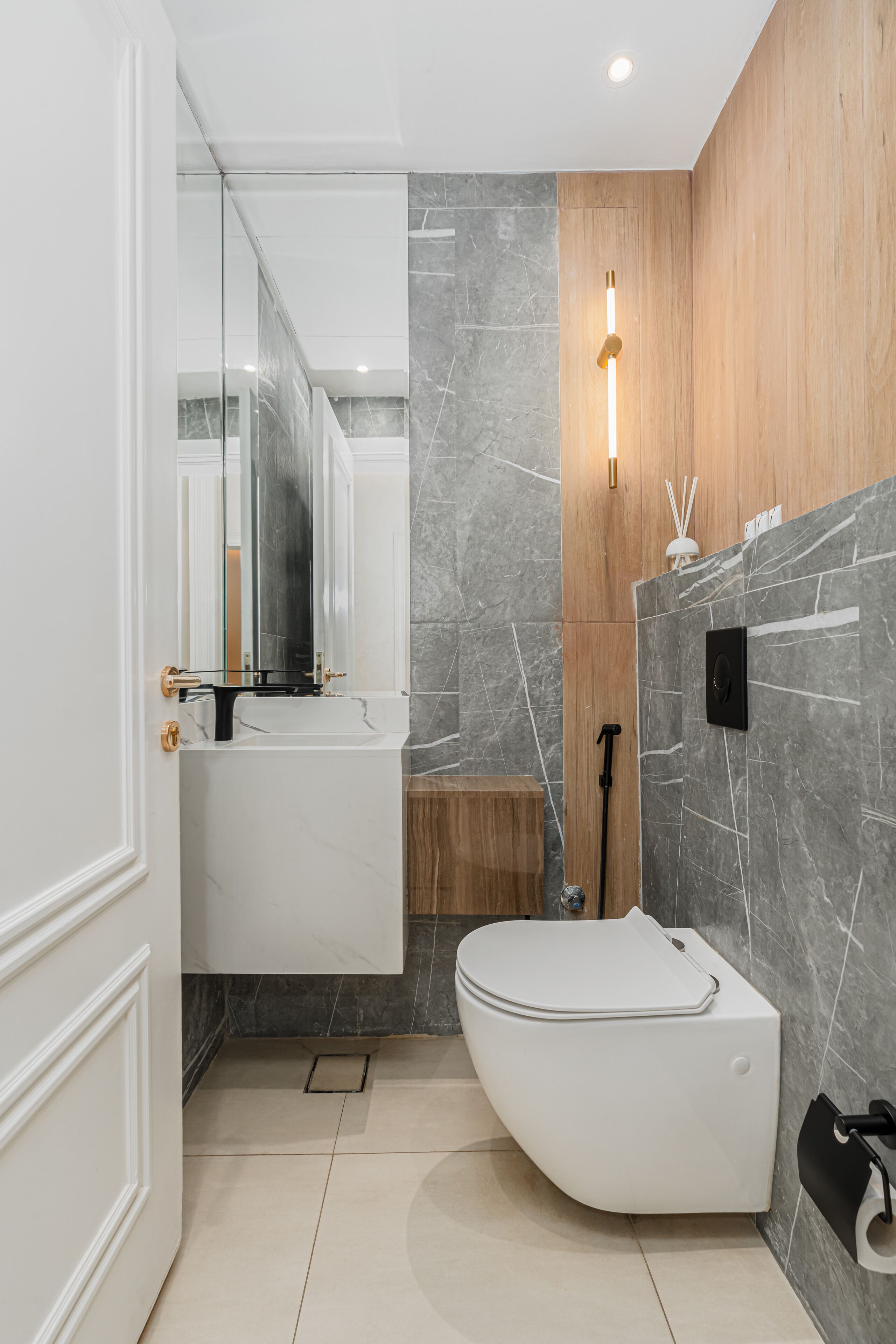 A modern bathroom with a white toilet, a glass-enclosed shower, and a marble-tiled wall.