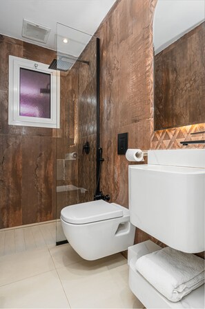 A modern bathroom with a glass shower enclosure, a white toilet, and a white sink with a towel. - Luxury Home: Dedicatedwork Space, Parking (Riyadh)