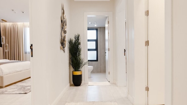 Un couloir moderne et bien éclairé, aux couleurs neutres, qui mène à une chambre et à une salle de bain.