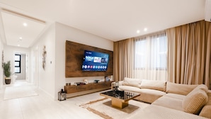 Un salon moderne avec un grand téléviseur à écran plat fixé au mur, un canapé et une table basse.