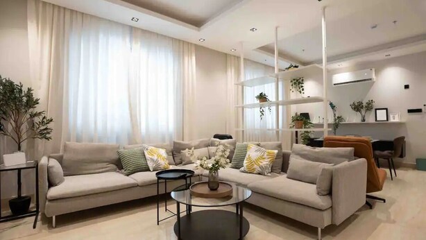 A modern living room with a sofa, coffee table, and shelves with plants. - Al Malqa Flat, Sleeps 4 With Free Parking (Riyadh)