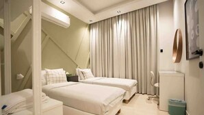 A modern hotel room with two beds, a small desk, a chair, and a toilet. - Al Malqa Flat, Sleeps 4 With Free Parking (Riyadh)