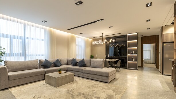 Uma sala de estar moderna com um sofá seccional, uma mesa de centro e um espaço para refeições.