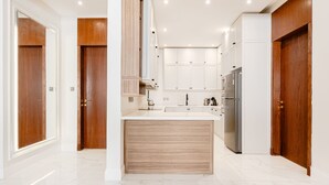 Una cocina moderna con gabinetes blancos, una isla central y un refrigerador de acero inoxidable.
