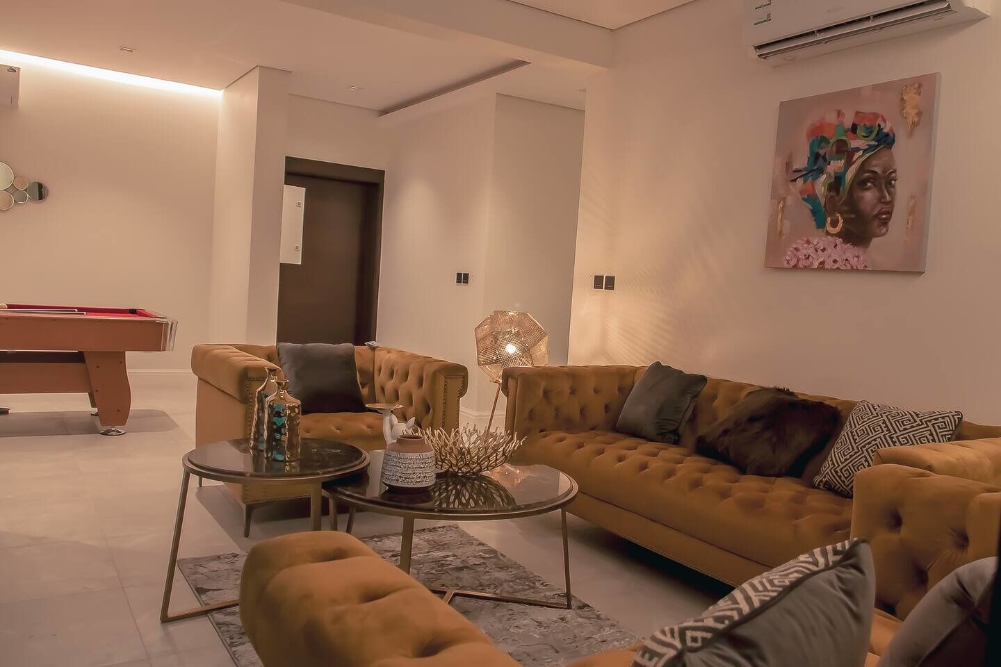 Una sala de estar moderna con sofá, sillón, mesa de centro y mesa de billar.