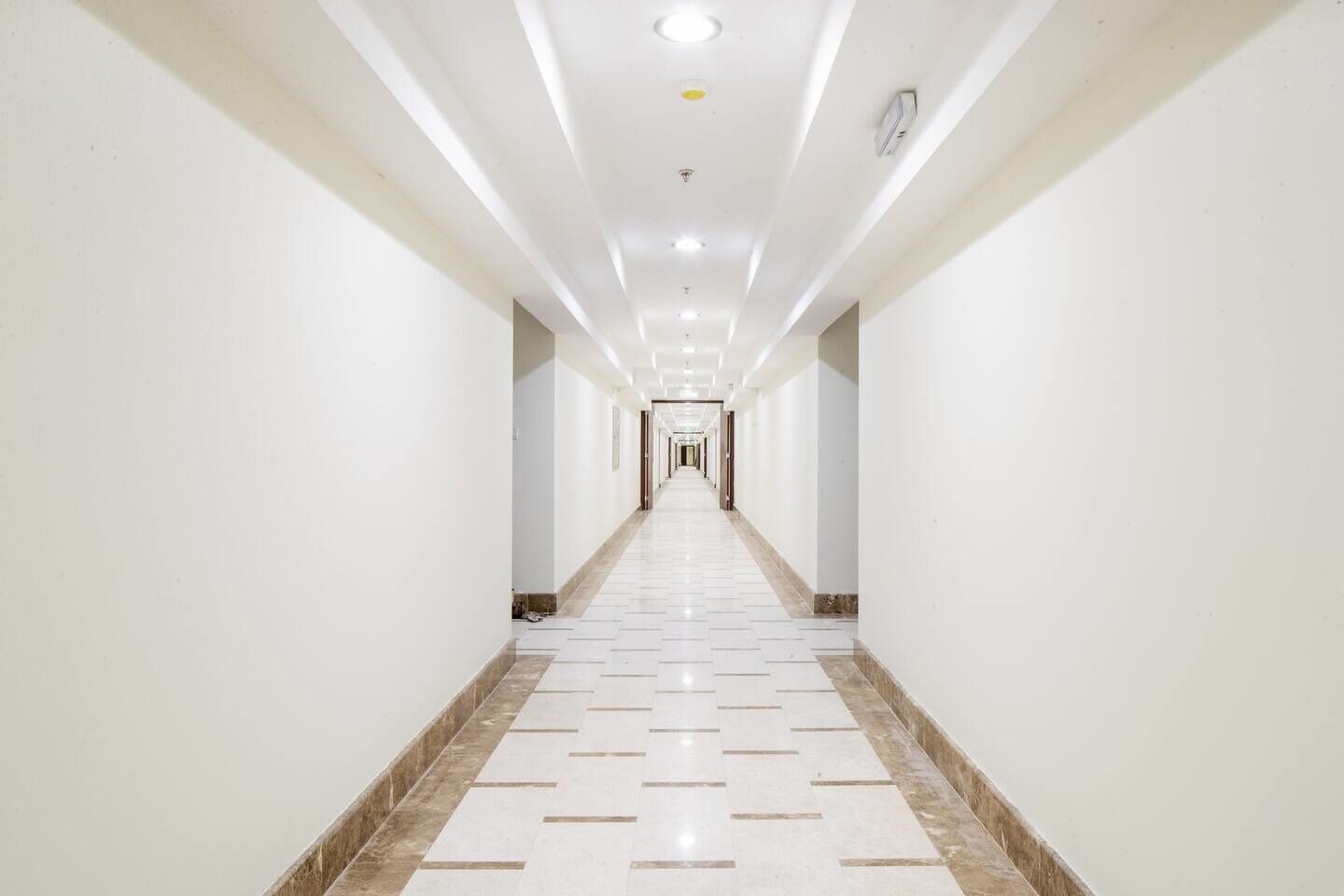A long, narrow hallway with white walls and a tiled floor.