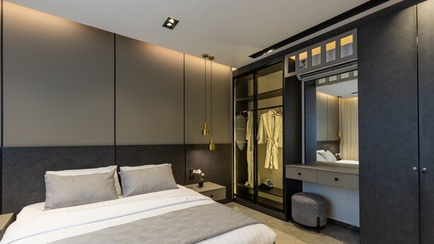 Et moderne soveværelse med en stor seng, et walk-in closet og et sminkebord med spejl.
