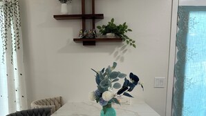Un coin repas avec une table en marbre, des chaises rembourrées et un vase rempli de fleurs.
