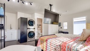 Een moderne slaapkamer met een bed, een wasmachine en een droger.