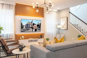 Uma sala de estar moderna com televisão de tela plana, um sofá, uma mesa de centro e uma escada.