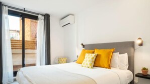 A hotel room with a bed, a nightstand, a wall-mounted air conditioner, and a view of a wooden staircase. - Private Terrace Dishwasher 3 Bedrooms (Barcelona)