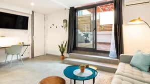 A modern living room with a sofa, a small coffee table, and a TV mounted on the wall. - Private Terrace Dishwasher 3 Bedrooms (Barcelona)