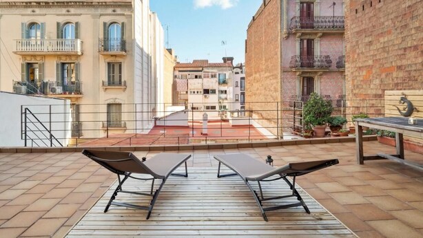 A rooftop terrace with two lounge chairs and a table, overlooking a cityscape with historic buildings. - Private Terrace Dishwasher 3 Bedrooms (Barcelona)