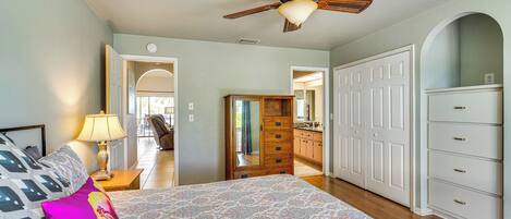 A bedroom with a bed, a ceiling fan, a dresser, and a walk-in closet.