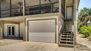 Een tweelaags huis met een ruime garage, een balkon met een ventilator en een trap naar de bovenverdieping.