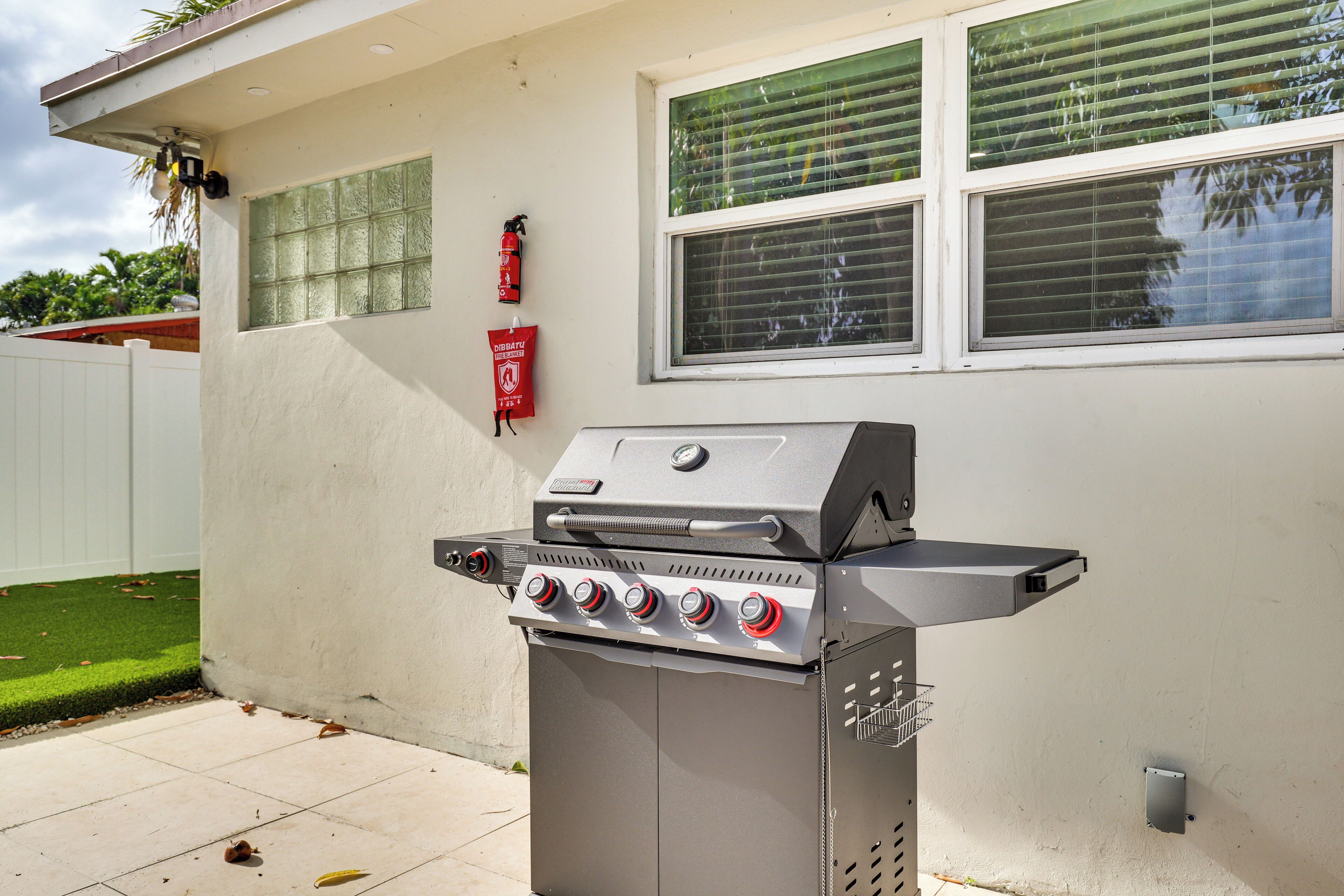 A barbecue grill with four burners, a control panel, and a side shelf.