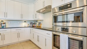 Una cocina moderna con armarios blancos, electrodomésticos de acero inoxidable y una encimera negra.