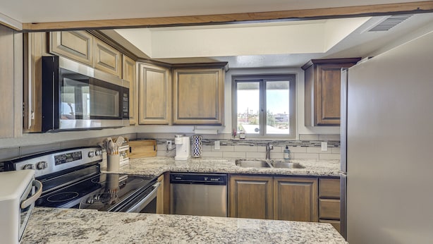 A kitchen with granite countertops, wooden cabinets, stainless steel appliances, and a window providing a view. - Lake Views & Boat Parking: Condo in Heart of LHC (Lake Havasu City)