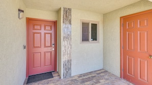 A hallway with two red doors, a small window, and a textured wall. - Lake Views & Boat Parking: Condo in Heart of LHC (Lake Havasu City)