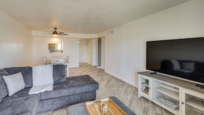 A living room with a gray sofa, a wooden coffee table, a TV on a wooden stand, and a ceiling fan. - Lake Views & Boat Parking: Condo in Heart of LHC (Lake Havasu City)