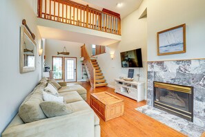 A spacious living room with a high ceiling, a wooden staircase, a fireplace, and a large window. - 1 Block to Inlet Beach: Brigantine Family Home (Brigantine)