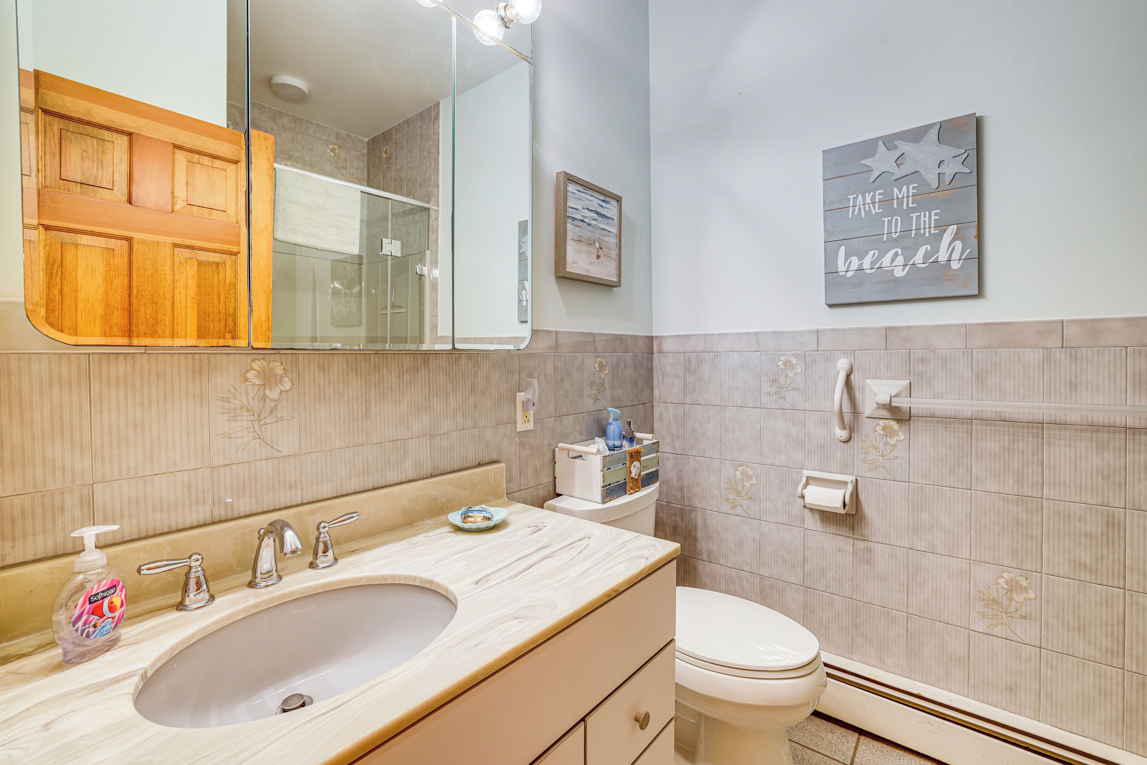 A bathroom with a sink, mirror, toilet, and a wall-mounted towel rack.