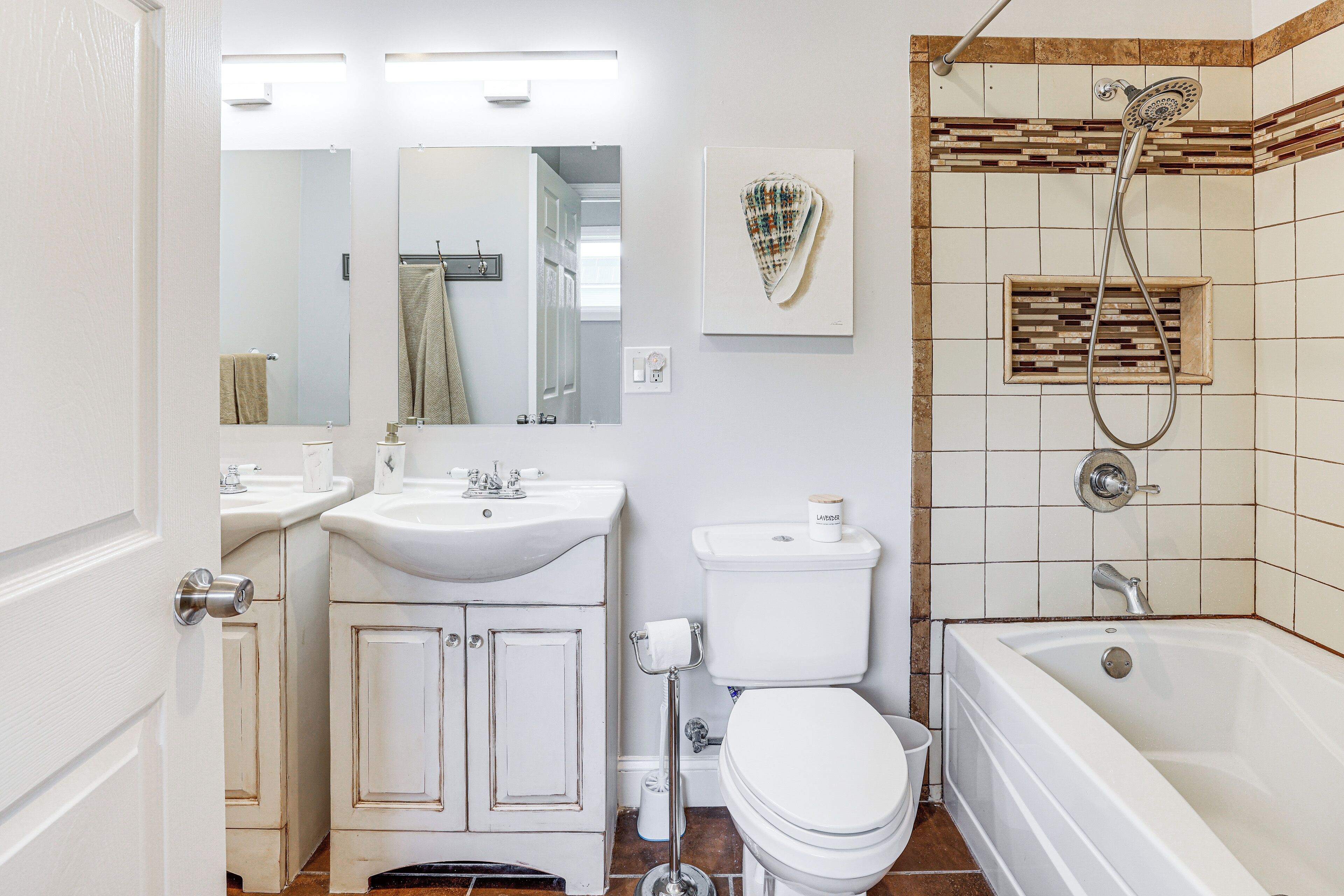 A bathroom with a toilet, sink, mirror, and shower.