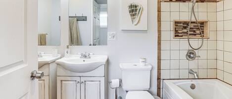 A bathroom with a toilet, sink, mirror, and shower.