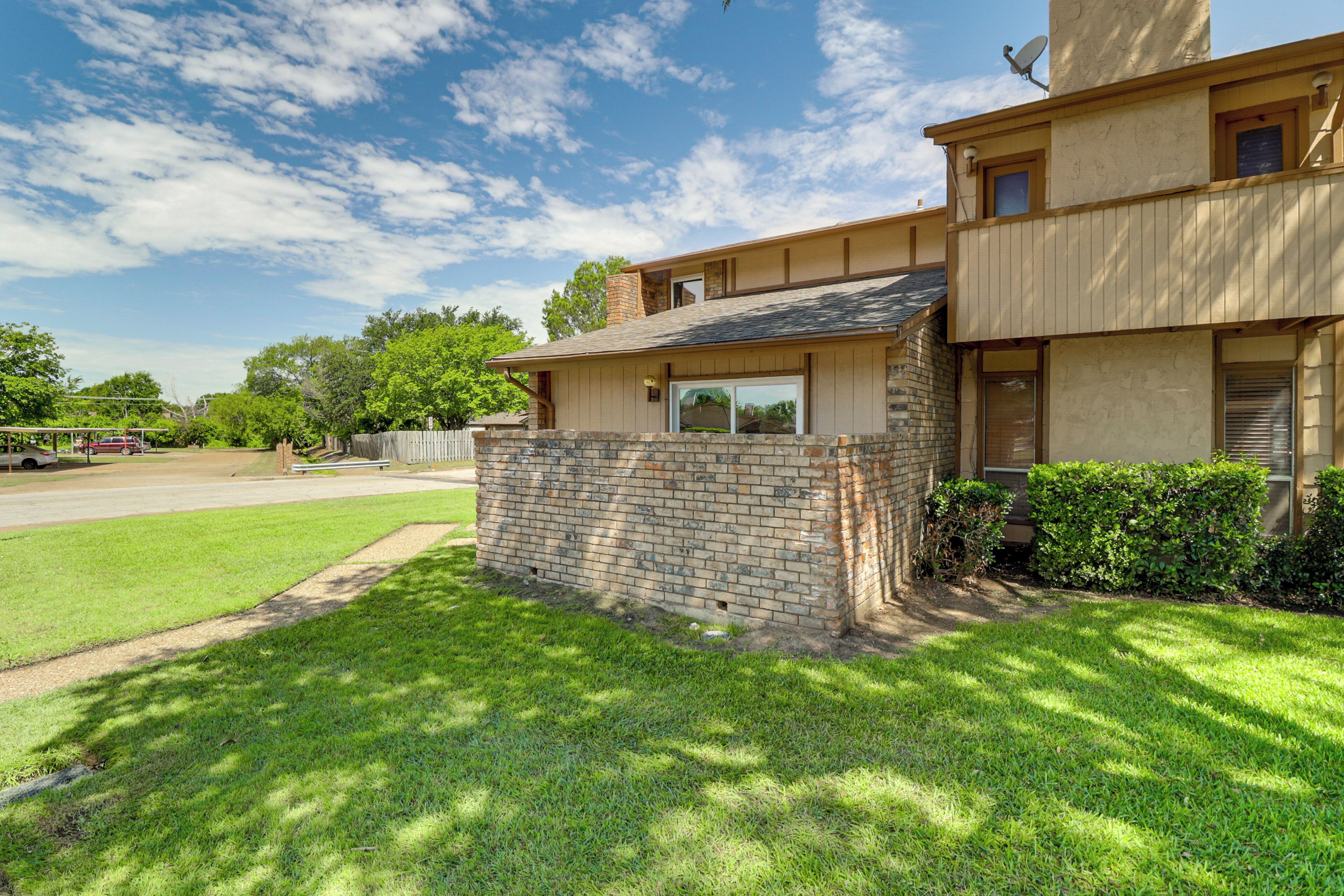 A two-story house with a brick exterior, a small front porch, and a satellite dish.