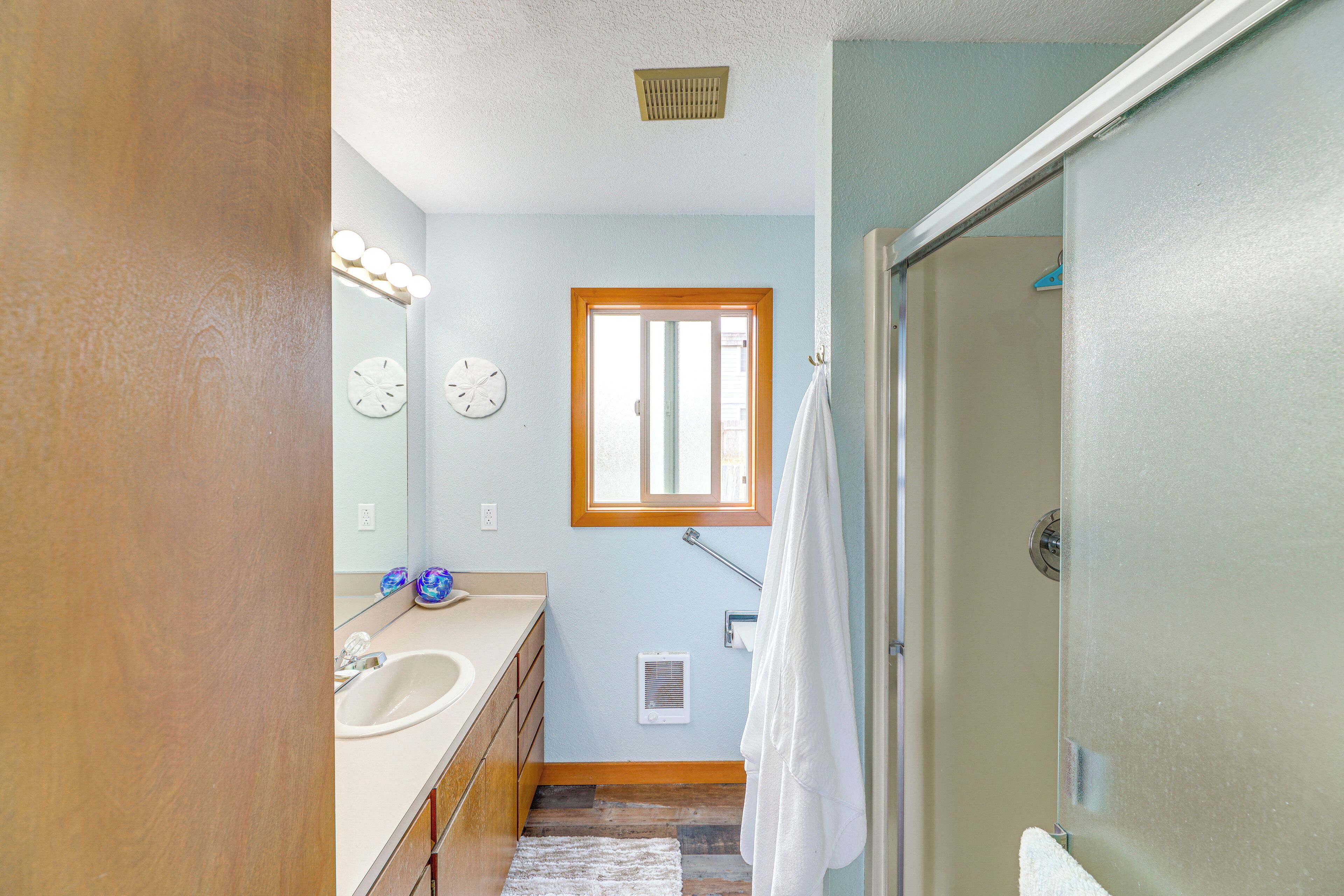 A bathroom with a sink, mirror, and a window.