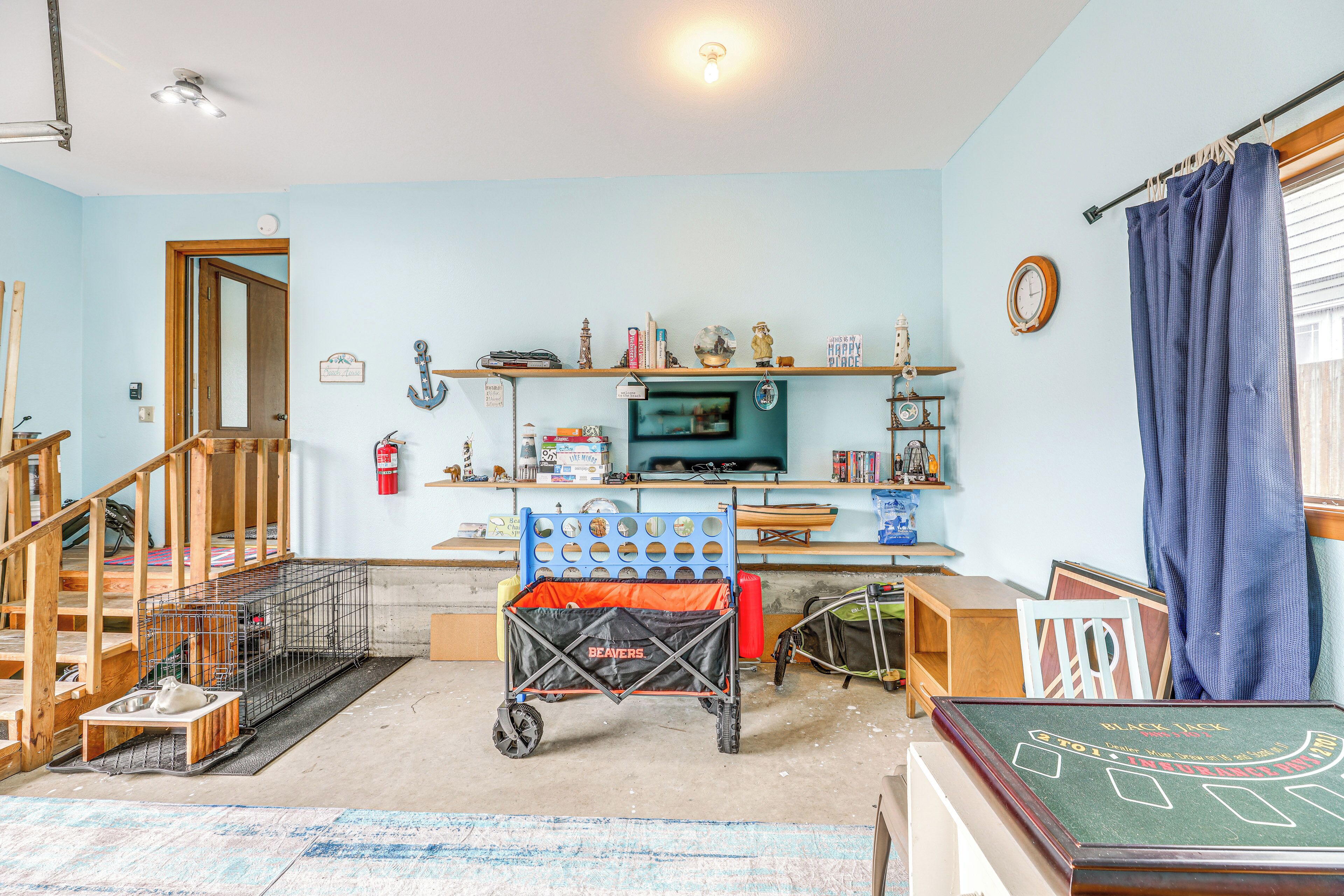 Une pièce avec un escalier en bois, une télévision, des étagères remplies de divers objets et une table de billard.