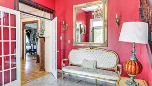 Une pièce avec un mur rouge, un canapé blanc, un miroir et une lampe.