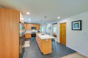 Une cuisine moderne avec des meubles en bois, un îlot central et un coin repas équipé d’une chaise.