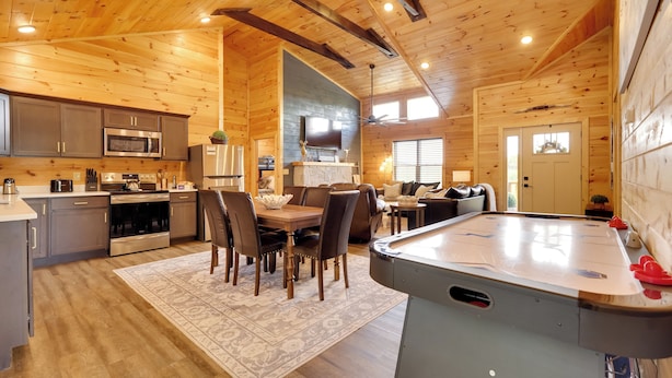 A spacious log cabin interior with a kitchen, dining area, and a pool table.