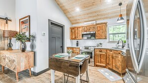 Una cocina moderna con armarios de madera, un refrigerador de acero inoxidable y un comedor con una mesa y sillas de madera.