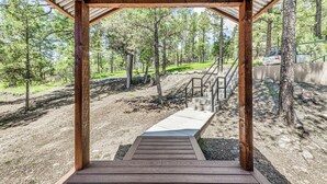 Una terraza cubierta de madera con un sendero de concreto que lleva a una escalera.
